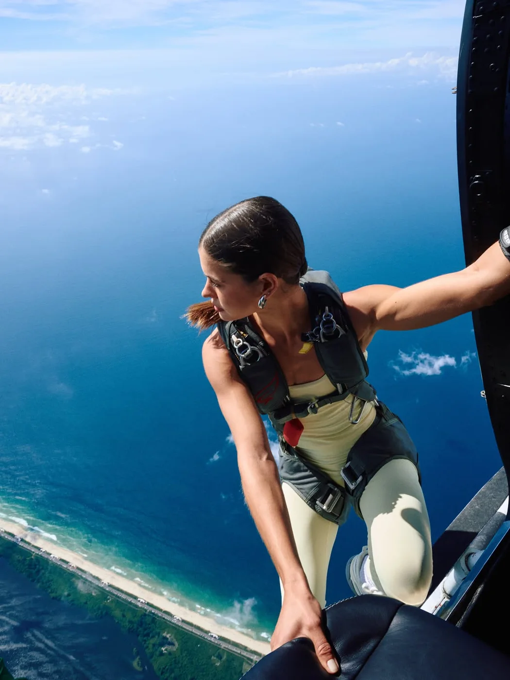 Sara Vidal equipada na porta do helicóptero sobre o Rio de Janeiro